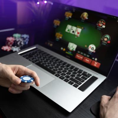 A young man playing online poker using a laptop.