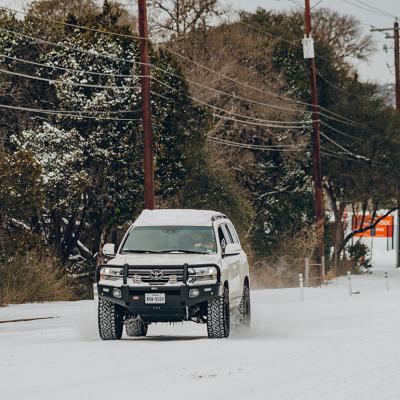 A white 4x4 truck braving thick snow on a Texas road after a blizzard.