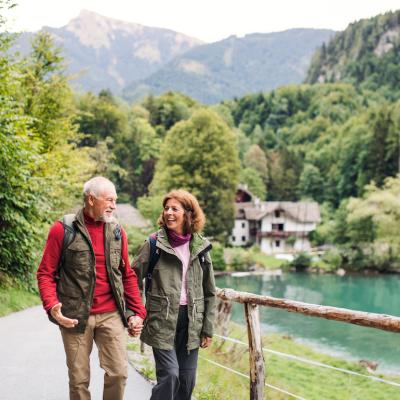 Senior couple hiking near a lake, holding hands, and enjoying the outdoors.