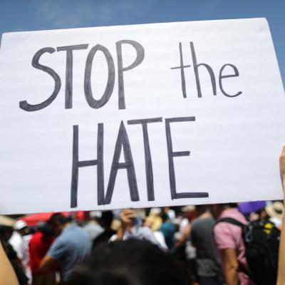 A demonstrator holds a sign reading 'Stop the Hate' at a protest.