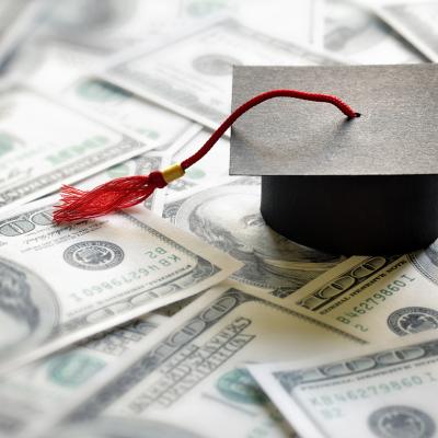 Conceptual image of college; a graduation cap over a pile of cash money.