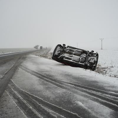 A car lying on its side after an accident in a snowy road.