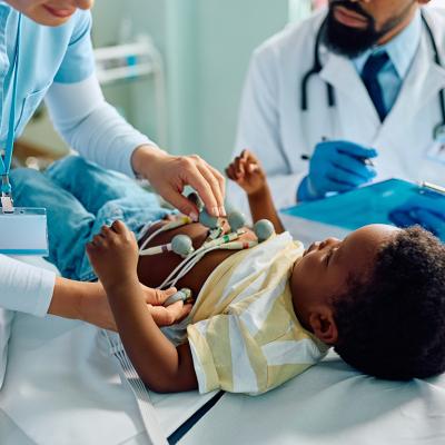 A nurse putting ECG electrode on an infant's chest during a medical examination at a clinic.