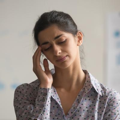 Person closing their eyes and touching their temples.