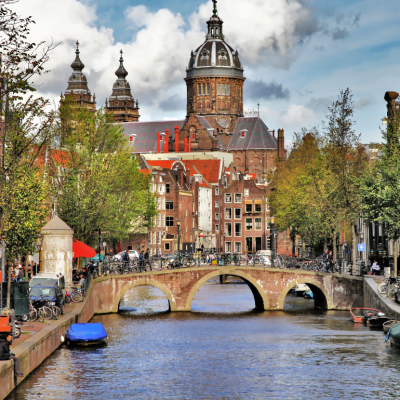 People walking over a bridge and on the streets by a canal in Amsterdam