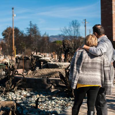 A couple looks at the ruins of their owned home caused by a fire disaster.