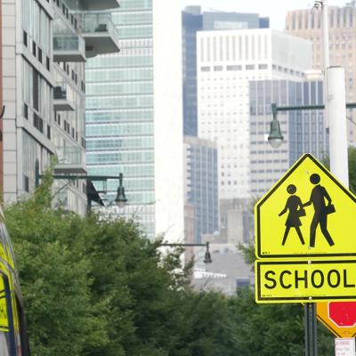 A yellow school zone sign for children's pedestrian crossing in a New York street.