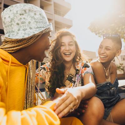 A group of three Gen Z friends laughing and hanging out in the city.