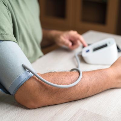 Young man getting his blood pressure checked at home with a digital monitor.