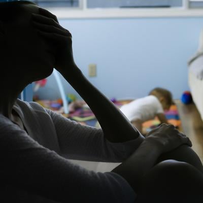 Silhouette of a stressed mother sitting at the corner of her baby's room.