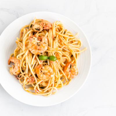 Shrimp scampi pasta on a white plate photographed from directly above.