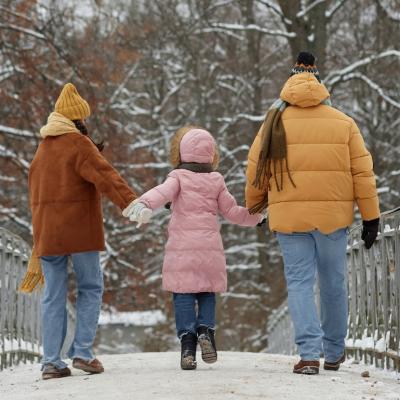 Back view of young family with child walking on bridge together in a small town.