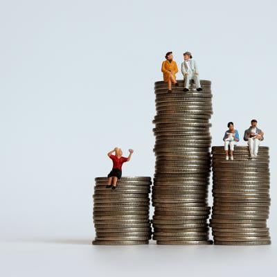 Small figures representing humans and different points in life on top of coins representing their typical amount of income and savings.