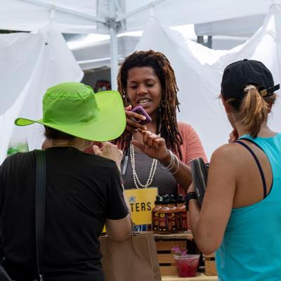 A vendor in the artist market area takes a mobile payment from a customer during the AthFest music and arts festival.