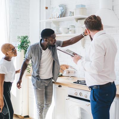 A couple inspects the kitchen of an apartment with a property manager.