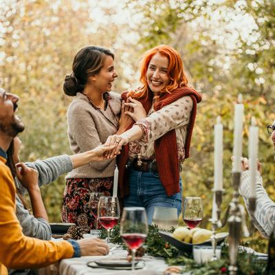 A lesbian couple showing off an engagement ring and celebrating a happy engagement with their friends.