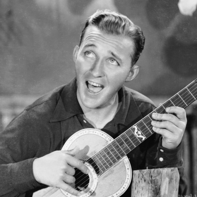 Actor and singer Bing Crosby (1904 - 1977) strums a happy tune on his guitar.