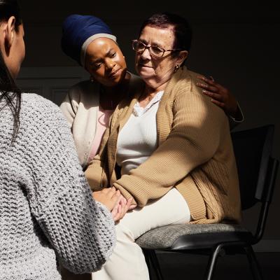 A senior woman in group support session with other women.