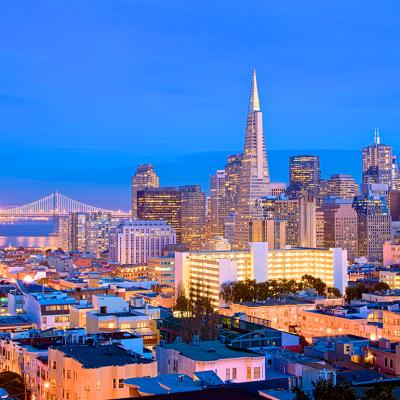 A cityscape view of skyscrapers and Golden Gate Bridge in San Francisco during dusk.