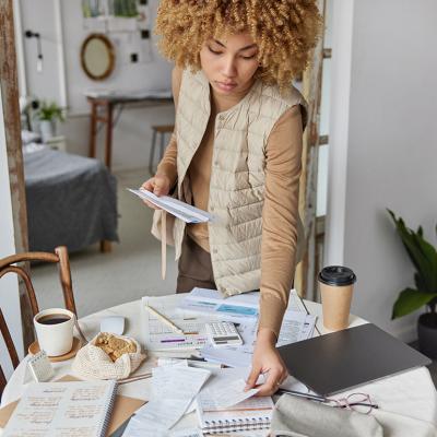 A young woman checks and organizes bills at home.