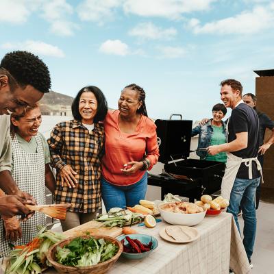 A multigenerational family bonds over food and happily engaging during a summer outdoor gathering.