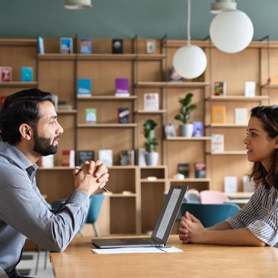 Employer and worker sitting at a wooden table talking.