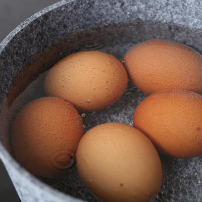 Five chicken eggs being boiled in a saucepan.