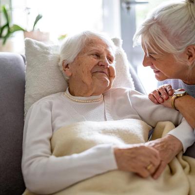 Elderly woman sits with her caregiver at her side.