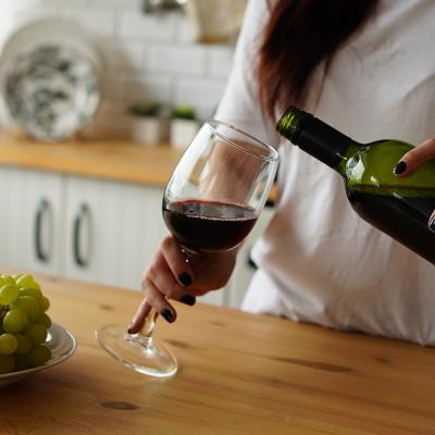 A woman pours a glass of red wine at home.