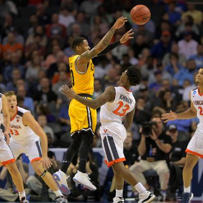 UMBC guard Jairus Lyles (10) and four UVA defenders during the 2018 Men's NCAA basketball tournament at the Spectrum Center in Charlotte, North Carolina.