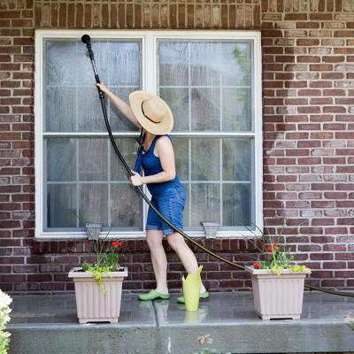 A woman washes the exterior and windows of her house at the start of spring season.