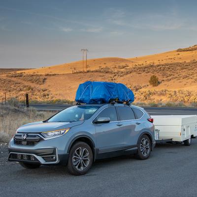 A blue Honda CR-V with a loaded roof rack and is used to pull a pop-up camper for a trip to rural eastern Oregon.