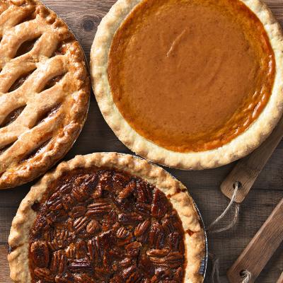 Apple, pumpkin and pecan pies on a wooden table.