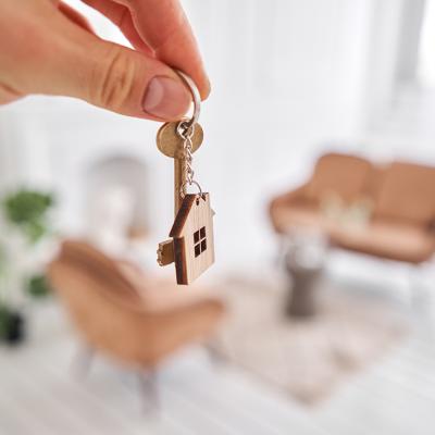 Property owner holds house keys over the backdrop of the home's living area.