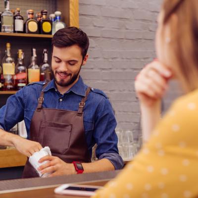Bartender kindly smiling at customer while making a drink.