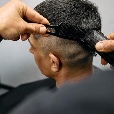 A barber expertly cuts a man's hair using clippers creating a smooth fade style.