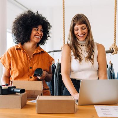 Two happy businesswomen preparing orders for e-commerce company.