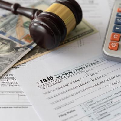 Tax law changes concept showing tax forms, bank notes, a calculator and a judge gavel.
