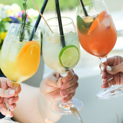 Hands clinking glasses of fruity cocktails together