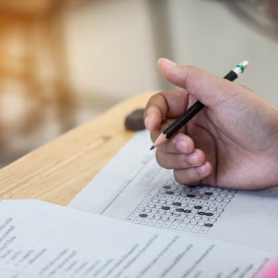 A student in a pink top filling out an answer form on an assessment test.