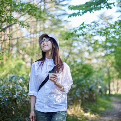 A young woman enjoying the view of the sky during summer in a forest.