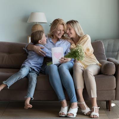 A mother receives Mother's Day gifts at home from her adult daughter and grandson .