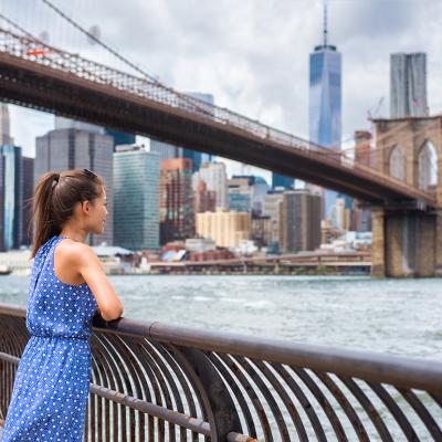 Woman touring NYC enjoying the Manhattan skyline from Brooklyn park.