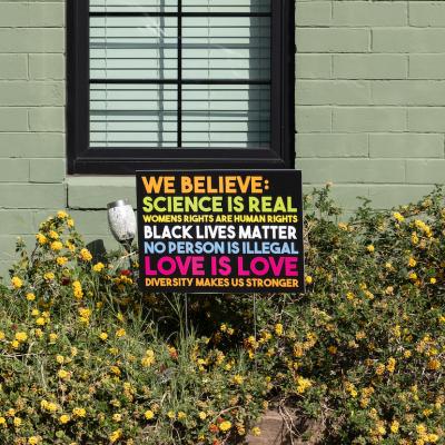 "We believe" yard sign that says, "Science is real, womens rights are human rights, black lives matter, no human is illegal, love is love, diversity makes us stronger” outside of a green home.
