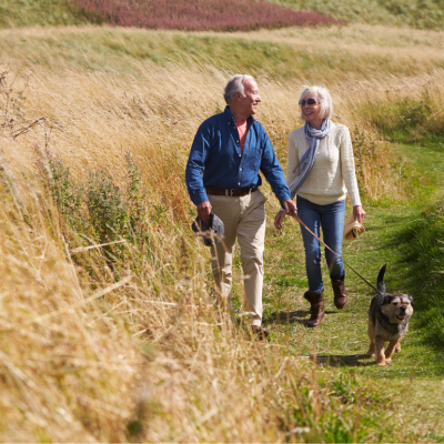 Senior couple walking their dog on a grassy countryside path