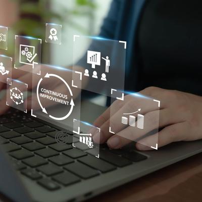 Continuous improvement concept illustrated by data icons superimposed over person typing on keyboard.