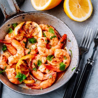 Garlic shrimp on frying pan with lemon and cilantro.