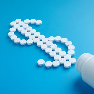 White pills spilling from a bottle forming a dollar symbol.