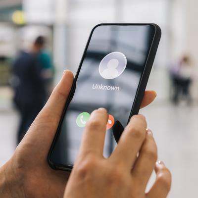 Person holding their phone with an incoming call from an unknown number.