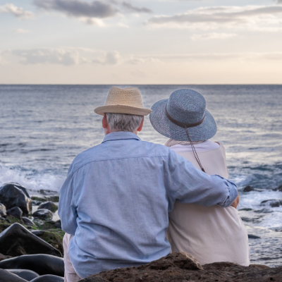 Elderly couple sitting on a rocky beach and looking at the horizon